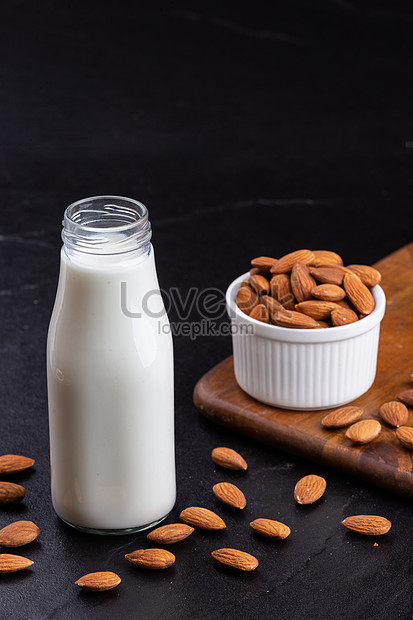 Free Photo  Milk carafe with bowl of almonds and bottle of milk high angle  view on a white wooden and piece of sack background