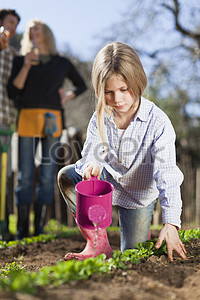 Девушка поливает цветы в саду stock pictures. & изображений