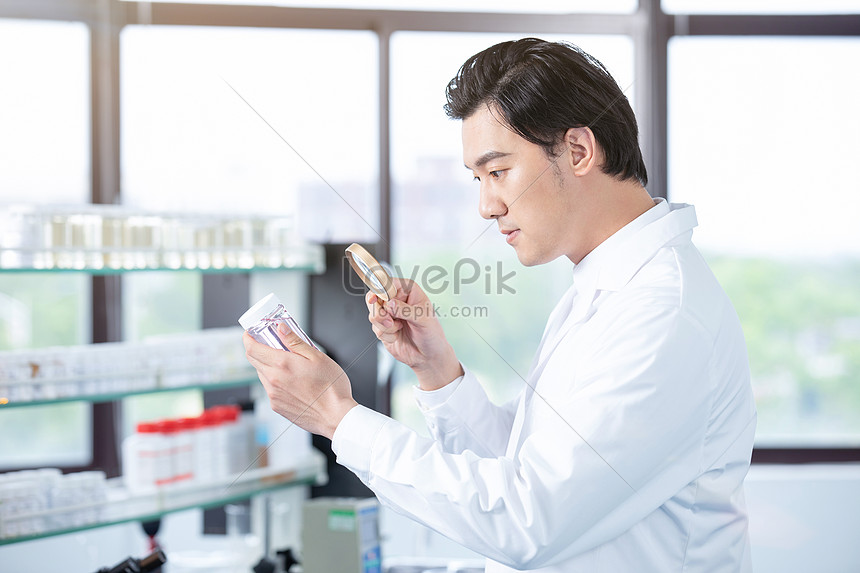 Male Medical Researcher Viewing Medicines With Magnifying Glass Picture ...