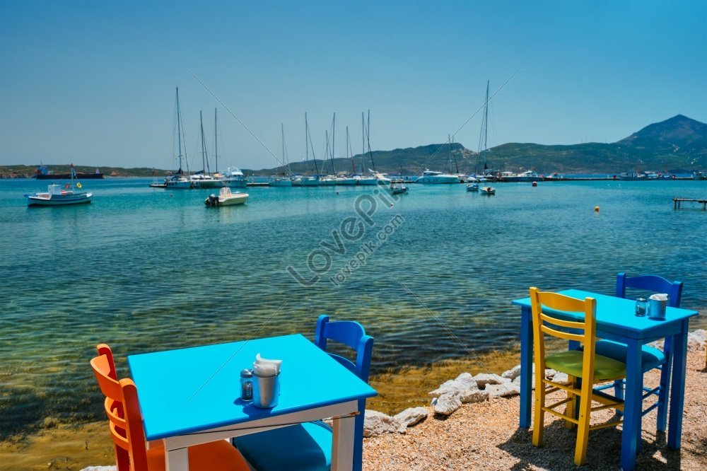 the cafe restaurant table at adamantas town on milos island with boats and yachts in the aegean sea background milos island photo, street, table background, yacht boat HD Photo