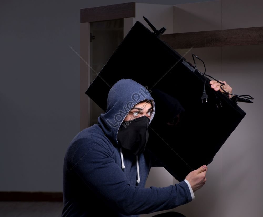 Ladrón enmascarado quita un televisor caro de la pared el concepto de robo  de apartamento