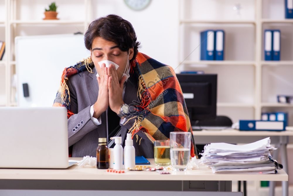 Young Male Employee Struggling At Workplace Man With Flu Present In ...