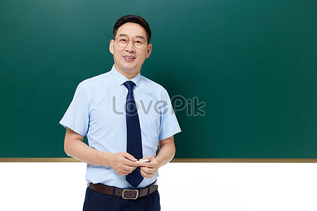 Middle-aged School Teacher Holding Chalk Standing In Front Of ...